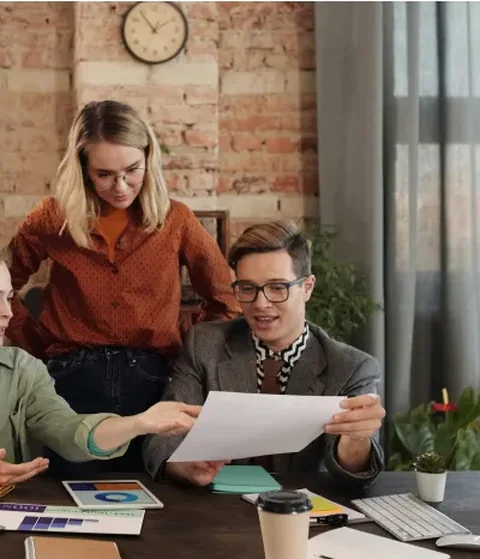Two colleagues reviewing printed work together at a desk